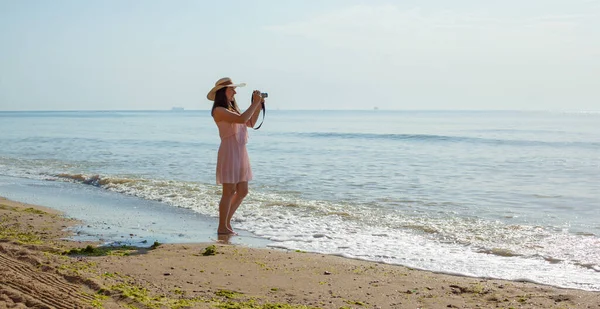 Chica en vestido rosa va en las olas del mar al mediodía. — Foto de Stock