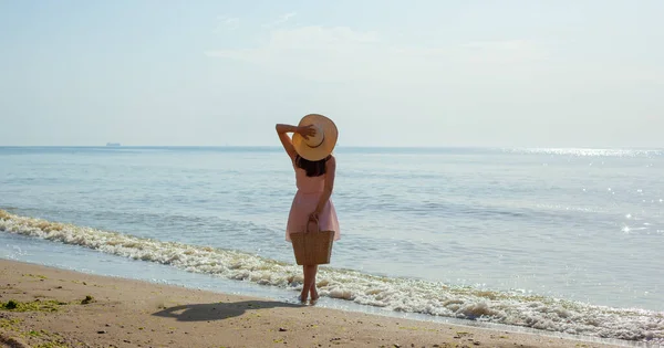 Chica en vestido rosa va en las olas del mar al mediodía. — Foto de Stock