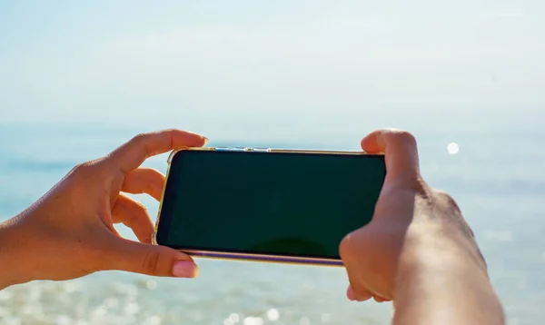 Close up foto di ragazze mani che tengono il telefono sullo sfondo del mare Foto Stock Royalty Free