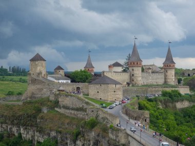 Kamianets Podilsky kalesi bulutlu bir yaz gününde. Ukrayna 'nın Khmelnytskyi bölgesindeki antik kale manzarası. Ortaçağ taşından, örümcekleri ve savunma kuleleri olan büyük bir kale..