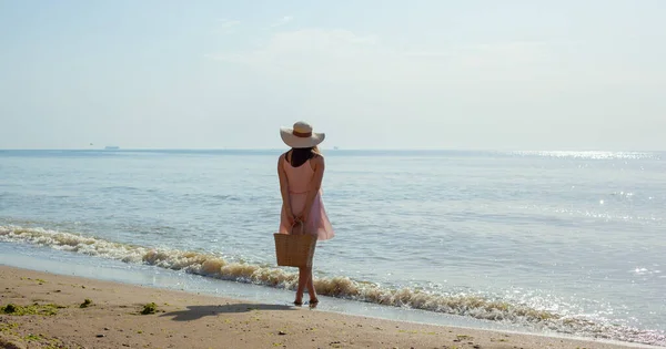 Chica en vestido rosa va en las olas del mar al mediodía. — Foto de Stock