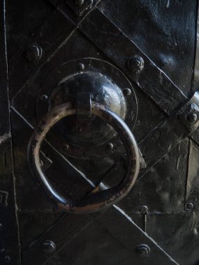 Eski bir ortaçağ kapısının yüzüğü. Ağır metal kapı. Arka plan için sanat duvarı deseni deseni. Siyah kapı, çelik çizgili geometrik desenlerle süslenmiş..