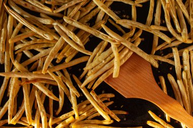 9. adım. Fırın tepsisinde pişmiş fasulye ve ahşap spatula. Kavrulmuş fasulye. Tabakta sarı ve yeşil fasulye, üst manzara. DIY. Sebze pişirme.