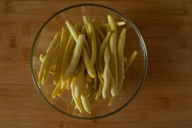 Kavanozda fasulye yıka ve boşalt. Kavrulmuş fasulye. Sarı ve yeşil fasulyeler ahşap masada, üst manzara. DIY. Ahşap arka planda sebzeler.