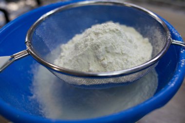 Beyaz unu, ahşap arka plandaki mavi kaseye yerleştirmek. Pasta ve fırın için hamur hazırlamak için un. Kek, turta ve bisküvi yapmak için adım at. Pişirme işlemi adım adım.