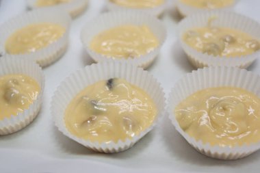 Kek hamuruyla dolu kağıt kutular, pişirilmeye hazır. Kuru üzümlü kek yapmak. Ev yapımı pişirme. Kek, turta ve bisküvi yapmak için adım at. Pişirme işlemi adım adım.