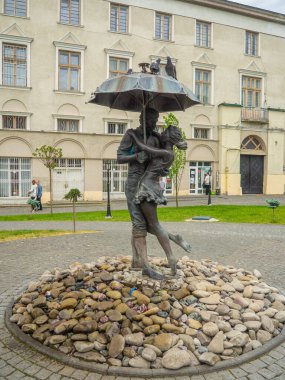 Drohobych, Ukraine - May 2022: Loving couple in the rain by sculptor Petro Smetana was unveiled on December 2019. Romantic fountain on Market square.