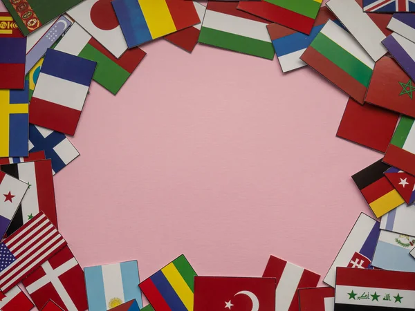 Pink background with many flags and copy space. Small flags of different countries on pink backdrop with empty place for your text. Multinational concept. Peace and friendship of cultures.
