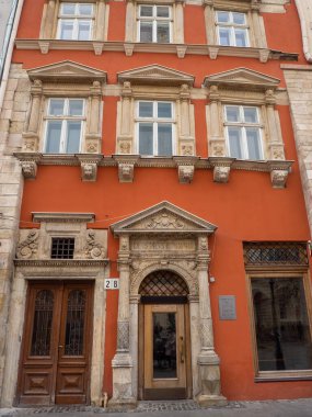 Lviv, Ukraine- July, 2022: Red facade of the house in the central part of the city. Decorative architecture with reliefs of a lion on the eaves and columns. Portal with columns around the doorway