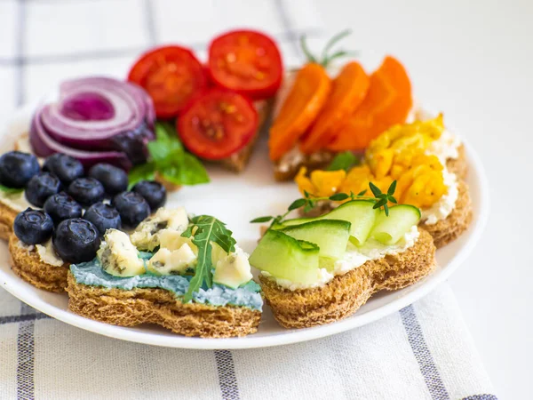 Rainbow sandwiches heart shape on white table. Breakfast bread rainbow sandwiches with colorful vegetables. Love, Valentines day food and LGBT pride flag concept. Copy space. Top view. Healthy food.
