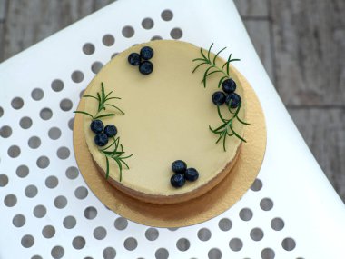New York style classical cheese cake on white dotted background. Homemade cheesecake decorated with blueberry berries and sprigs of rosemary. Cooking desserts and cakes. Confectionery. Top view.