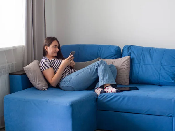 Woman Dark Hair Jeans Shirt Lying Blue Sofa Her Living — Stockfoto