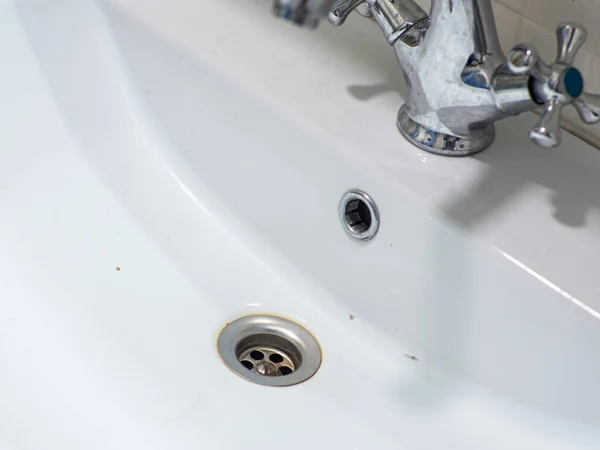 Dirty white sink. Open drainage. Untidy. Muddy. Stainless. Washbowl. The washbasin is dirty, unhygienic, has scale and rust. Bathroom cleaning concept. Domestic bath drain sink.