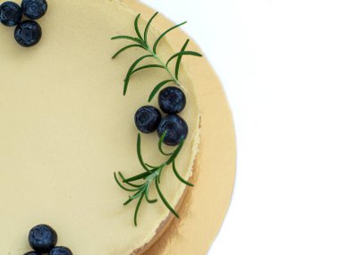 New York style classical cheese cake on white background. Homemade cheesecake decorated with blueberry berries and sprigs of rosemary. Cooking desserts and cakes. Confectionery. Close up.