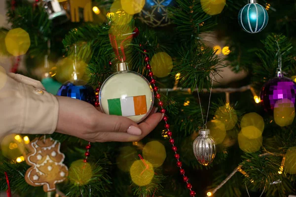 Крупным Планом Девушки Держат Руках Рождественский Шар Елки Флагом Ирландии — стоковое фото