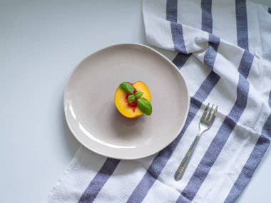 Sarı nefis nektarin ve bej tabakta yeşil fesleğen, beyaz masa üzerinde çizgili havluyla çatal. Diyet konsepti. Üst Manzara. Kilo verme konsepti. Uzayı kopyala, düz yat. Sağlıklı yemek ve yemek planı.