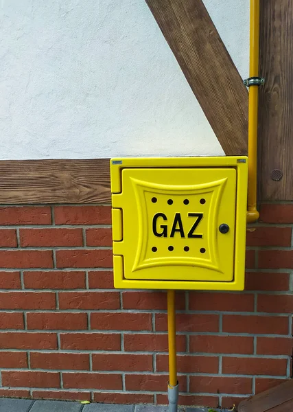 Outdoor metal gas connection box at the wall. Letters in Polish , Gaz means Gas. Yellow gas distribution box a gas installation to households on a facade of a building.