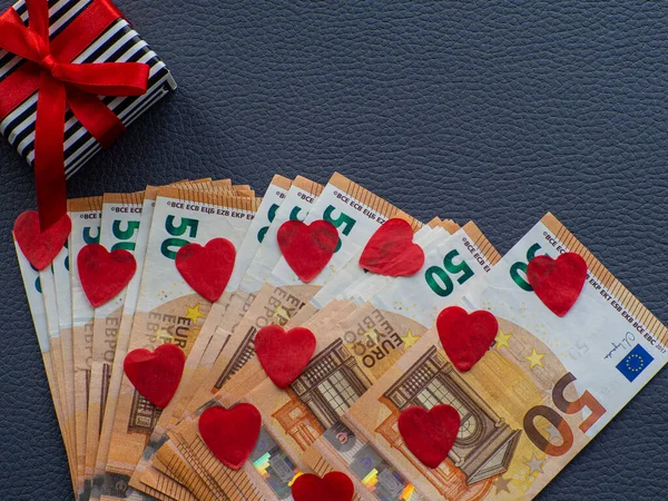 Euro money and red hearts for background. The concept of cash costs for the purchase of gifts for Valentines Day, love and money. Shopping, prices, sales, discounts, holiday gifts, congratulations.