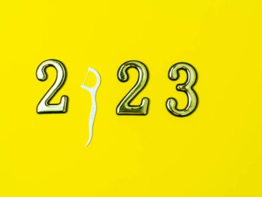 2023 ve diş konsepti. 2023 ve beyaz diş ipi çubuğuyla yakın plan fotoğrafını çek. Sıfır yerine sarı arka planda fotokopi alanı olsun. Noel kartı. Mutlu Noeller ve mutlu yıllar.