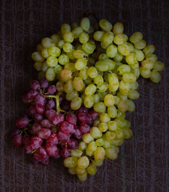 Masanın üzerinde yeşil ve kırmızı üzümler var.
