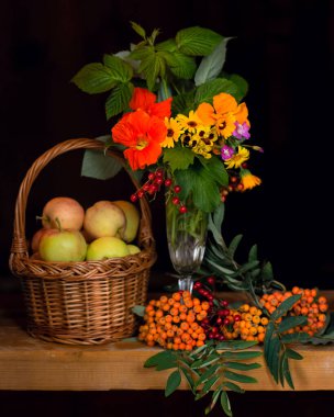 Bankta bir sepet elma ve bir buket çiçek var.