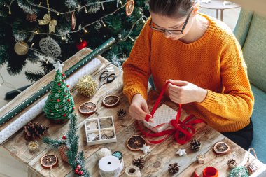Yılbaşı hediyesini yeni yıl süslemeleriyle saran genç bir kadın.
