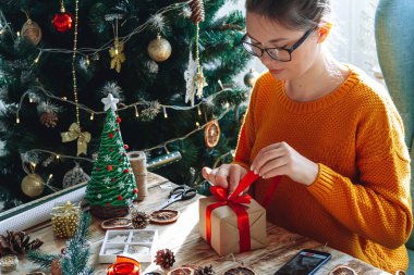 Yılbaşı hediyesini yeni yıl süslemeleriyle saran genç bir kadın.