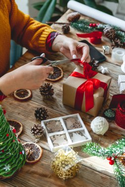 Yılbaşı hediyesini yeni yıl süslemeleriyle saran genç bir kadın.