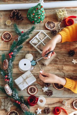 Yılbaşı hediyesini yeni yıl süslemeleriyle saran genç bir kadın.