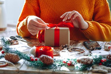 Yılbaşı hediyesini yeni yıl süslemeleriyle saran genç bir kadın.