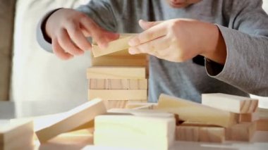 Çocuk evdeki kanepede oturan tahta bloklardan bir kule inşa etti.