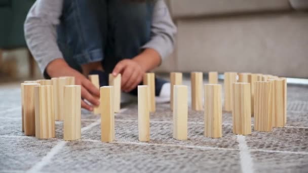 Kind duwen houten blok en start domino-effect. Houten blokken die in een ketting vallen — Stockvideo