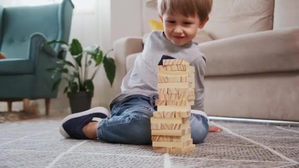 Παιδική συντριβή ξύλινο πύργο Jenga κάθεται στο πάτωμα στο σπίτι — Αρχείο Βίντεο