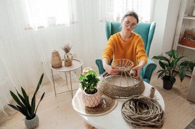 Kadın evde jüt ipten el yapımı diy lamba yapıyor.