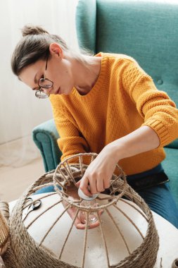 Kadın evde jüt ipten el yapımı diy lamba yapıyor.