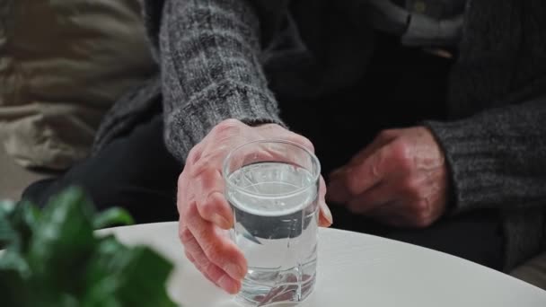 Les personnes âgées prennent un verre et de l'eau potable assis sur le canapé à la maison — Video