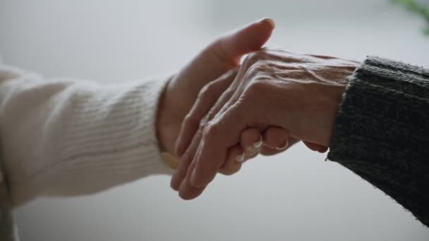Old hands of elderly senior in the young female hands of caring daughter, slow motion. Support and care for elderly parents — Stock Video