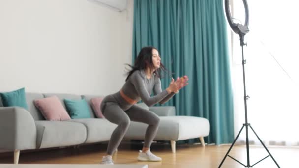 Attraktiv kvinnelig virtuell trening hjemme med smarttelefon – stockvideo