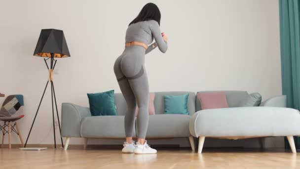 Joven mujer deportiva glutes sentadillas entrenamiento rutina de la mañana en la sala de estar — Vídeos de Stock