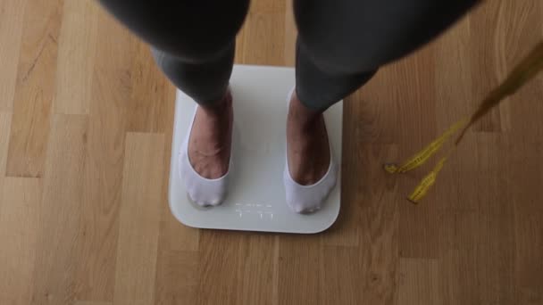 घरी वजन स्केल वर शरीर वजन मोजणारी स्त्री — स्टॉक व्हिडिओ