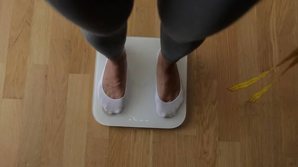自宅で体重計で体重計を測定する女性. ロイヤリティフリーのストック画像