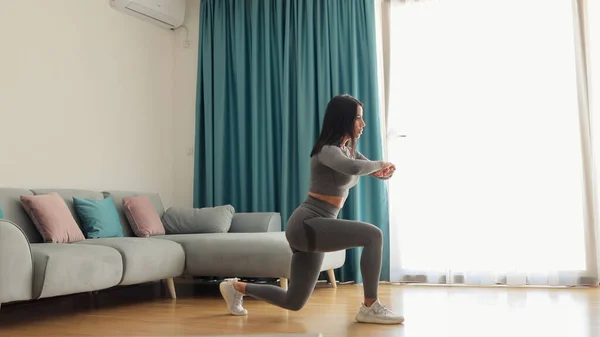 Athlétique femme sport séance d'entraînement à la maison, squats. Entraînement à domicile. — Photo