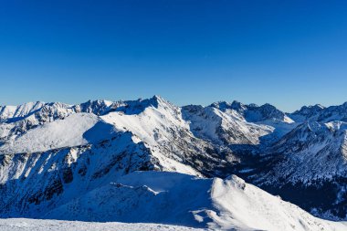 Polonya Tatraları 'nda karla kaplı ve buzlu yürüyüş yolları ve çevresindeki yüksek tepelerin manzarası..