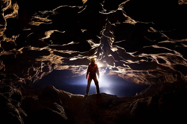 Espeleólogo em uma caverna nos raios de luz — Fotografia de Stock