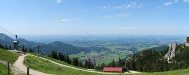 Yukarı Bavyera, Almanya, 4 Haziran 2022, Kampenwandbahn dağ istasyonundan Chiemgau alp eteklerine kadar Mslarn Alm köyü, Aschau köyü ve yaz gökyüzünde birkaç paraşütçü.
