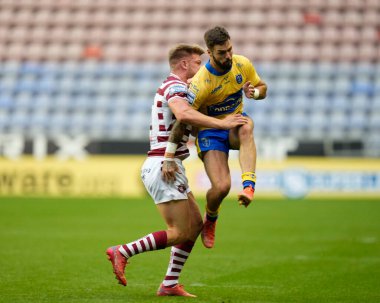 Morgan Smithies #14 of Wigan Warriors puts in a hit on Will Dagger #19 of Hull KR as he kicks the ball