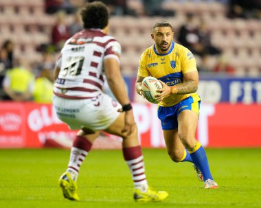 Elliot Minchella #17 of Hull KR runs at Patrick Mago #10 of Wigan Warriors 