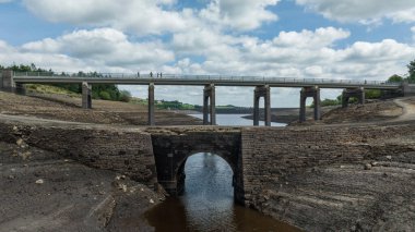 A man and his daughter on an old bridge thats usual submerged under water is full exposed as water in the reservoir is severally depleted at Baitings Reservoir near Ripponden West Yorkshire, UK on the 01/08/2022 