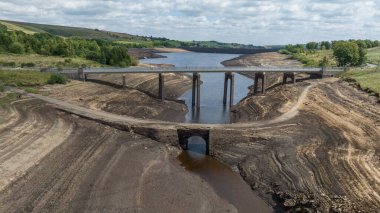 A man and his daughter on an old bridge thats usual submerged under water is full exposed as water in the reservoir is severally depleted at Baitings Reservoir near Ripponden West Yorkshire, UK on the 01/08/2022 