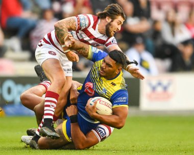 Thomas Mikaele #33 of Warrington Wolvesis tackled by Joe Shorrocks #22 of Wigan Warriors
